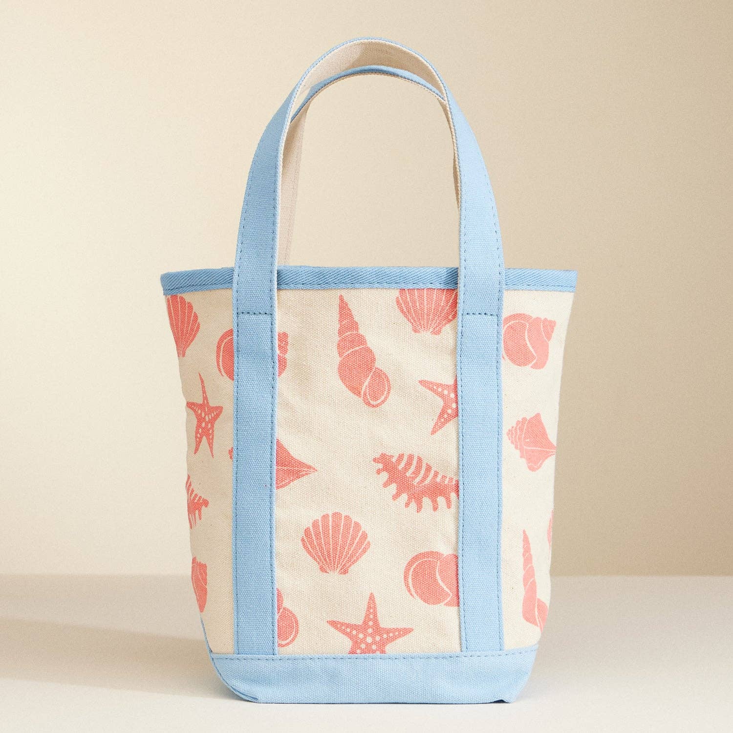Tote bag with shell pattern and blue accents on a beige background